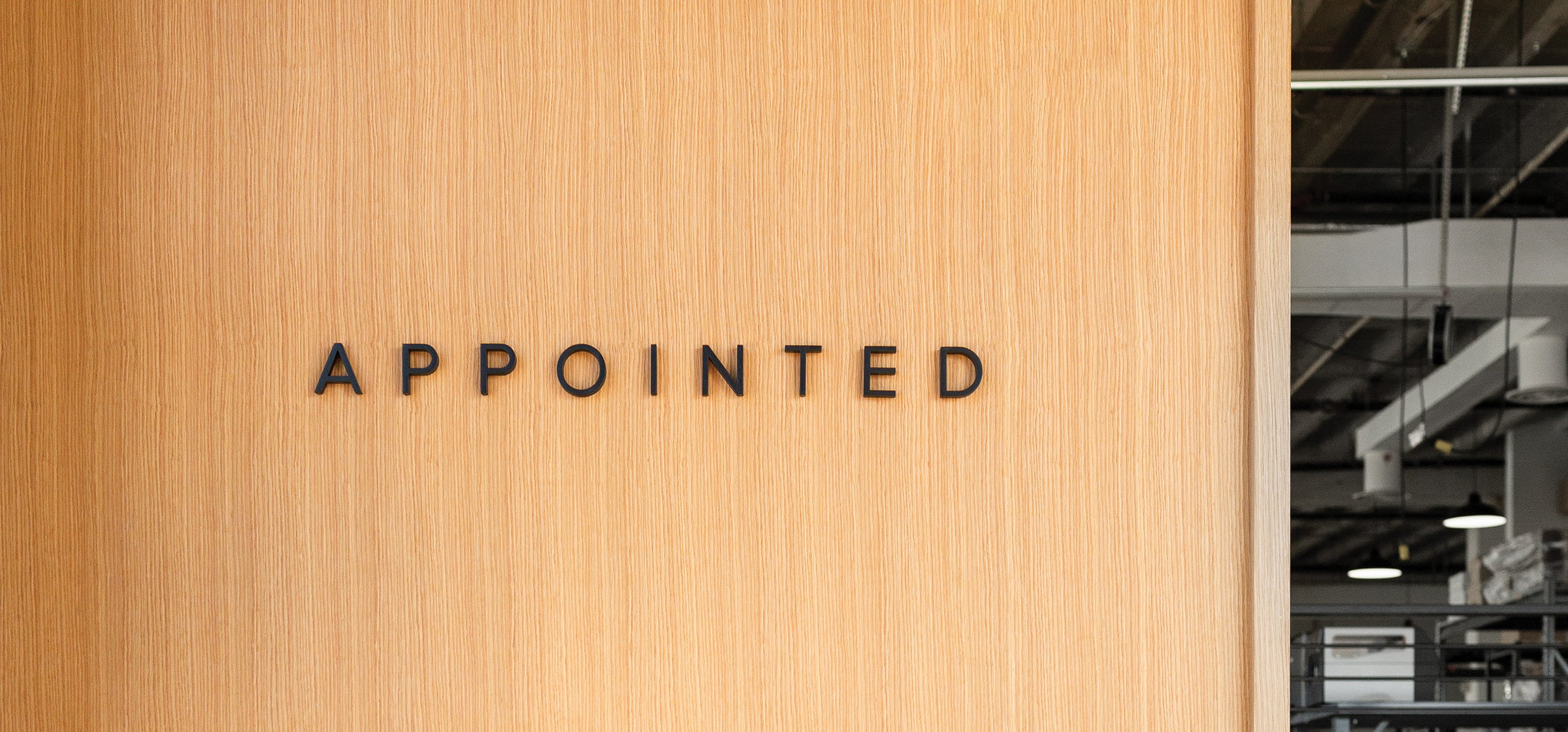 The Appointed District Shop wall at checkout shows a sneak peak of our behind-the-scenes production studio