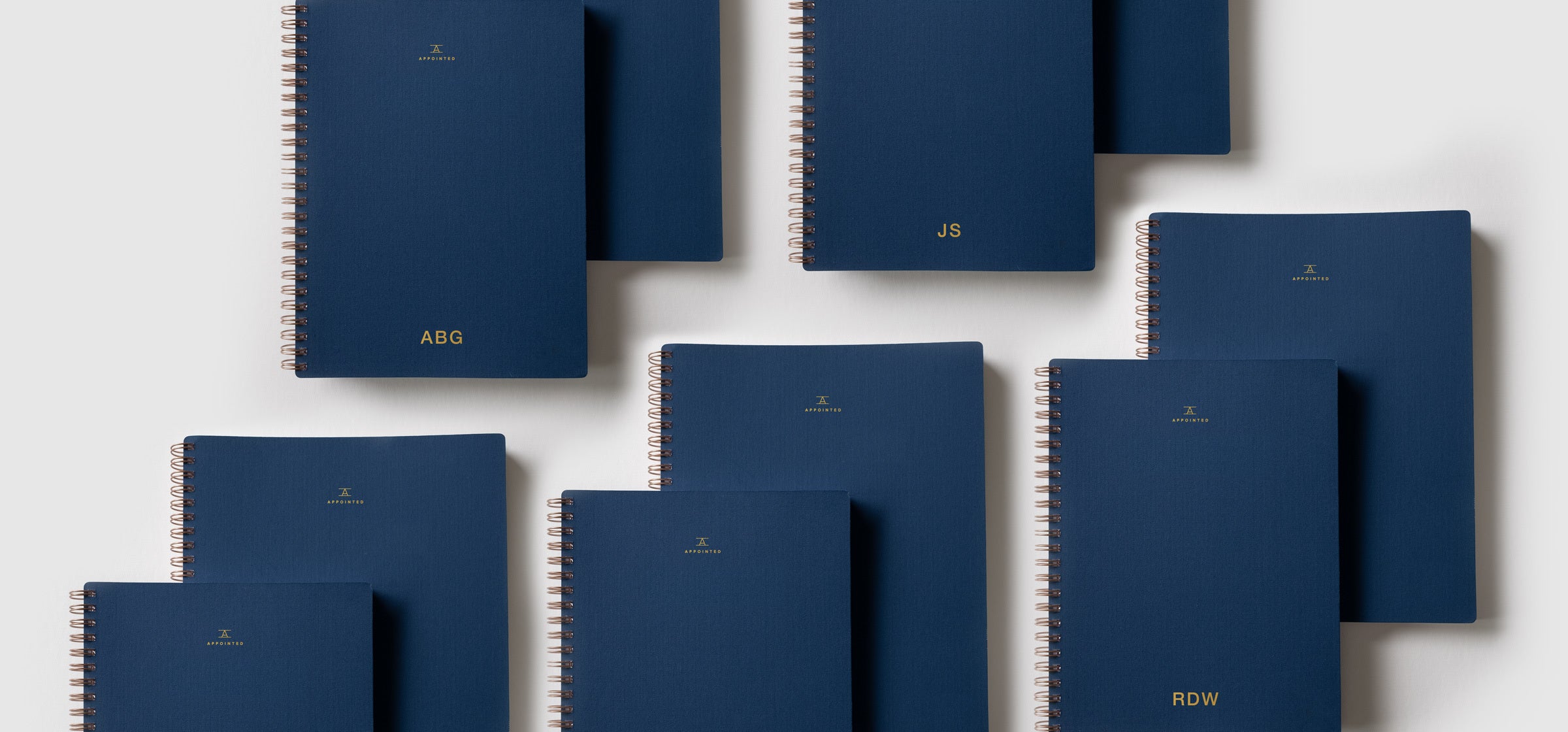 An assortment of Oxford Blue Appointed products featuring custom logo lie against a light gray background.