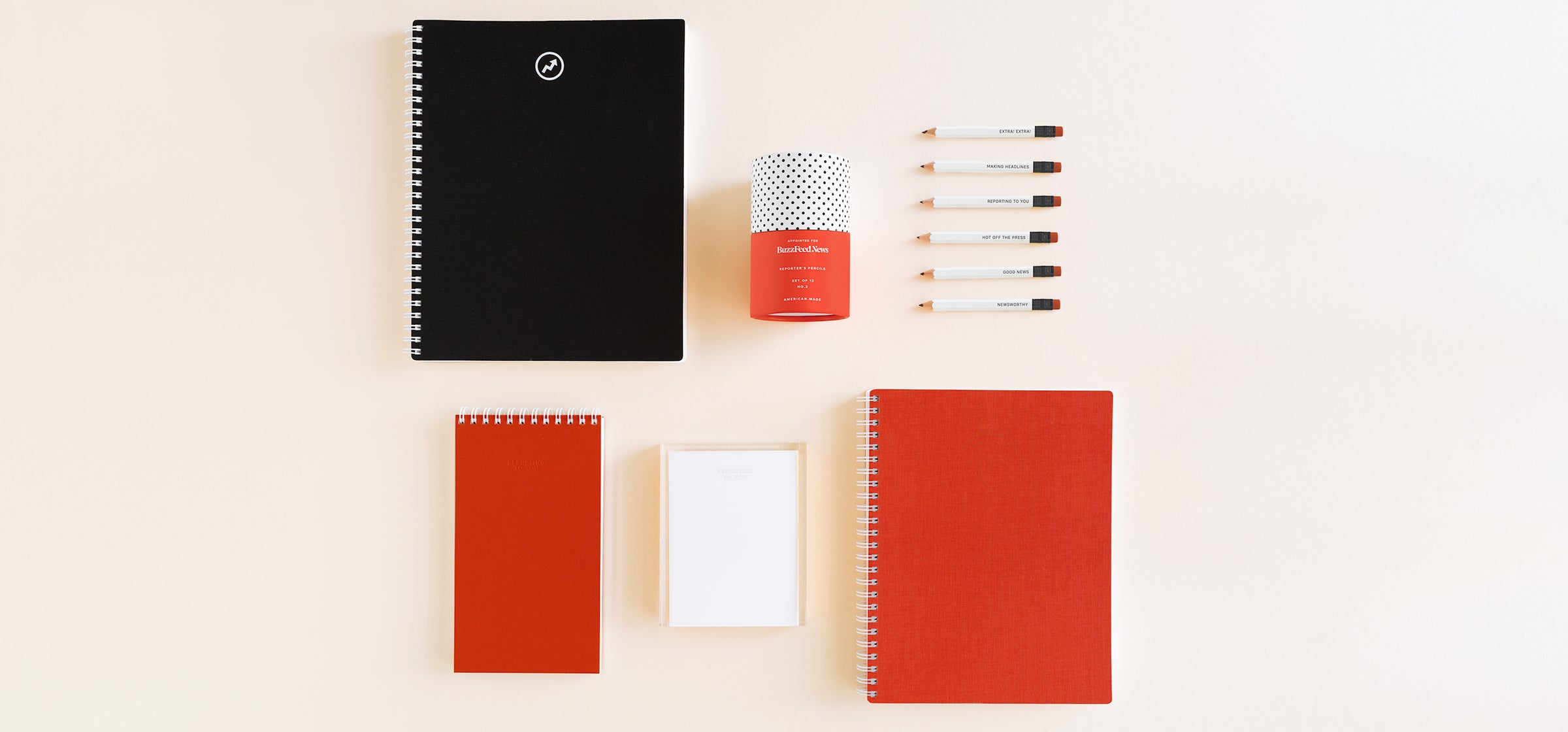 The Appointed for BuzzFeed News "Reporting To You" collection lays flat on a cream background, including various stationery & desk accessories in black, red, and white