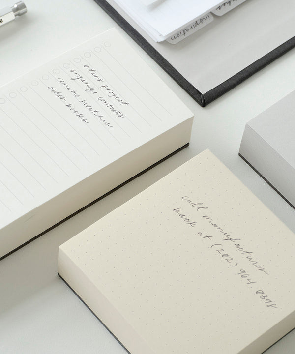 The Memo Pad set in neutrals sits staggered against a white background. It is filled in with written text in pencil.