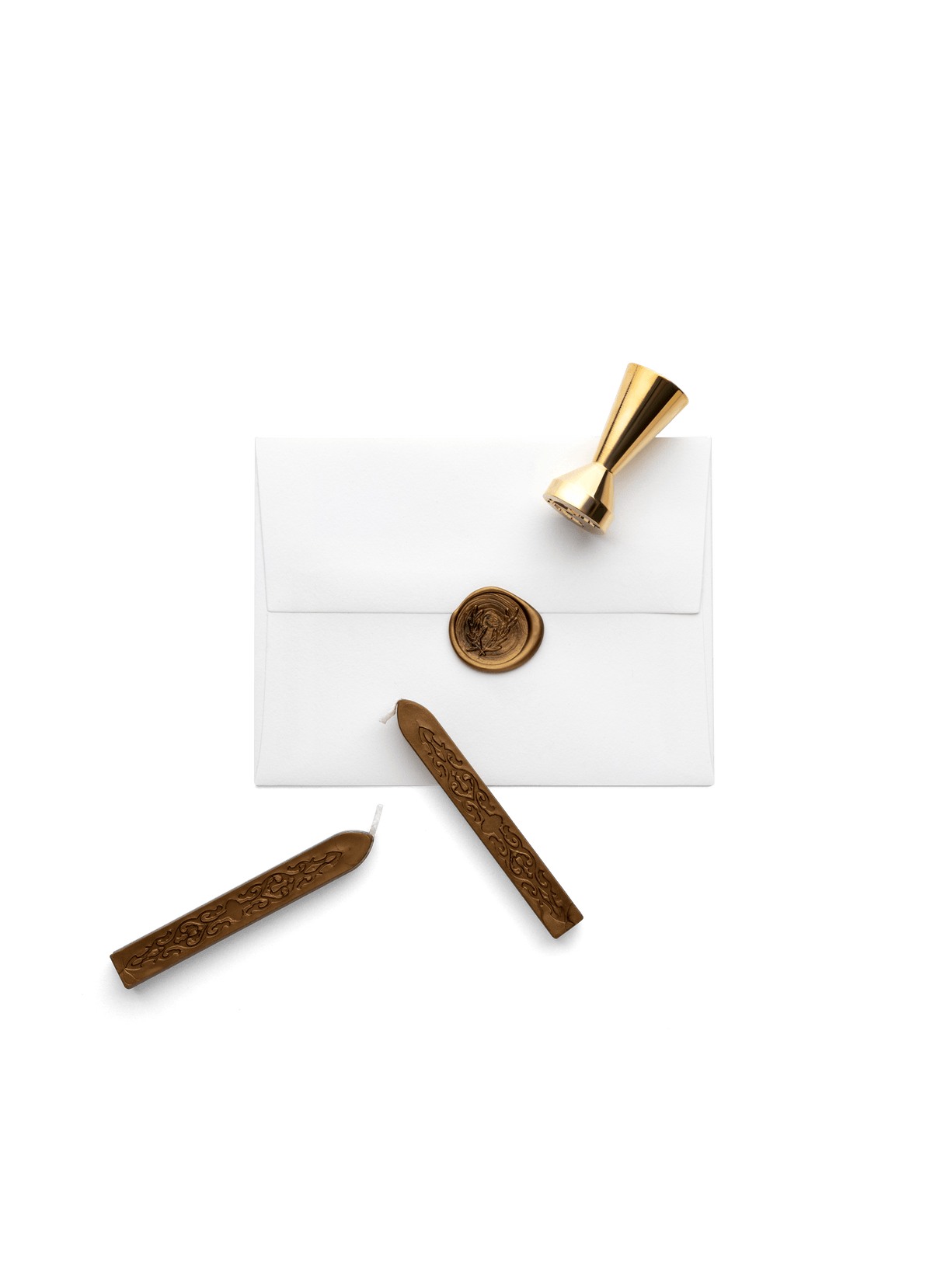 Two wax sticks and the brass seal laying on top of an envelop showing the seal